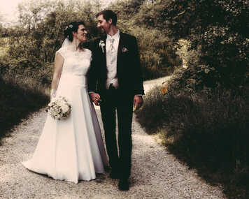 Ein Brautpaar geht am Hochzeitstag einen romantischen Weg entlang